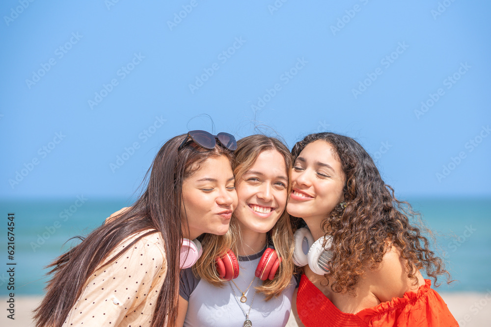 Three friends hugging posing for the camera on the beach Three friends hugging posing for the camera on the beach