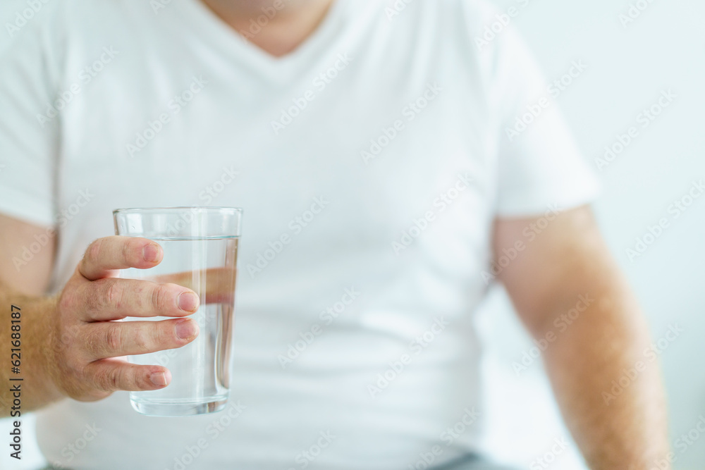 Happy cheerful oversize large belly man wake up in the morning and sitting on the bed then drinking a water in a glass. Caucasian white fat man drinks a water in a drinking glass in every morning. Happy cheerful oversize large belly man wake up in the morning and sitting on the bed then drinking a water in a glass. Caucasian white fat man drinks a water in a drinking glass in every morning.