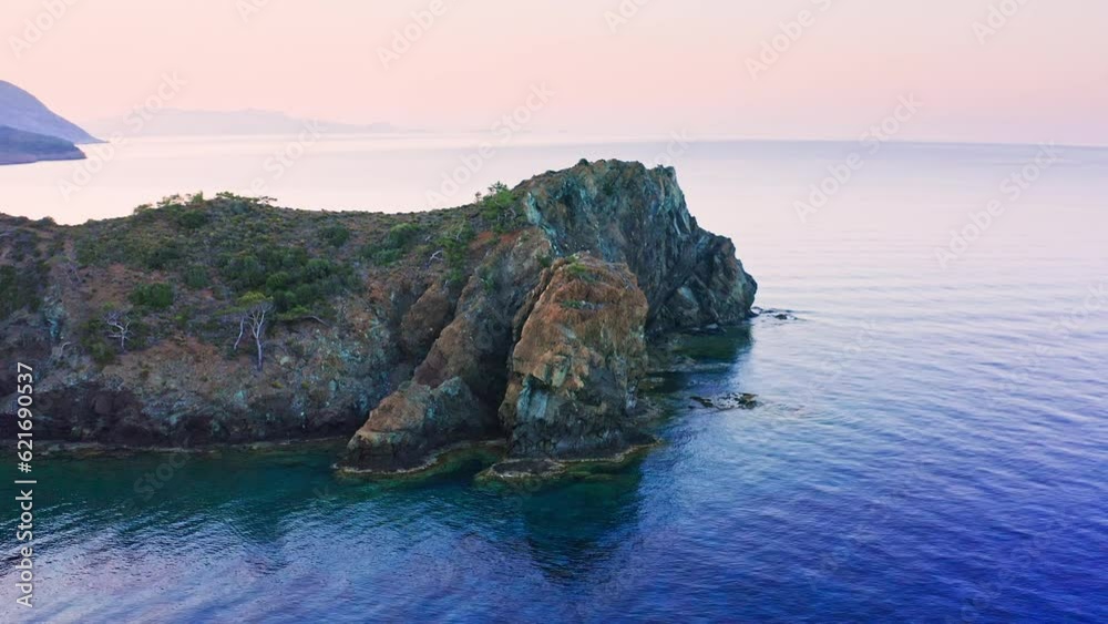 Rocky escarpment protruding into calm sea at morning dawn, Mesudiye, Datça