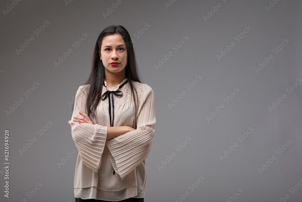 Confident Filipina boss in beige blouse, grey background