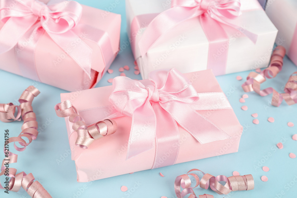 Gift boxes with bows, confetti and serpentine on blue background, closeup Gift boxes with bows, confetti and serpentine on blue background, closeup