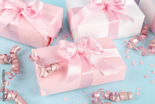 Gift boxes with bows, confetti and serpentine on blue background, closeup
