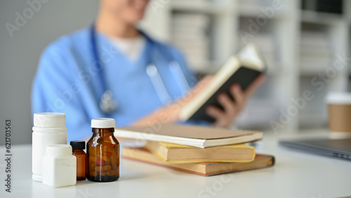 Obraz na plátně Close-up image of pill bottles and medical books on a table in a doctor's office
