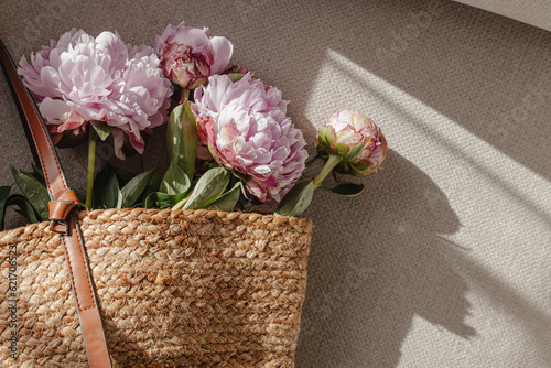 Fototapeta Naklejka Na Ścianę i Meble -  Pink peonies in the straw bag, summer lifestyle