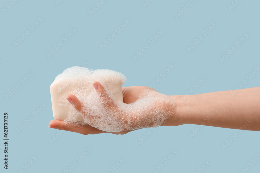 Hand with soap on light blue background