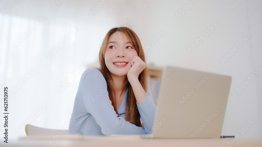Young asian woman working at home. Happy female using computer laptop on desk at house Young asian woman working at home. Happy female using computer laptop on desk at house