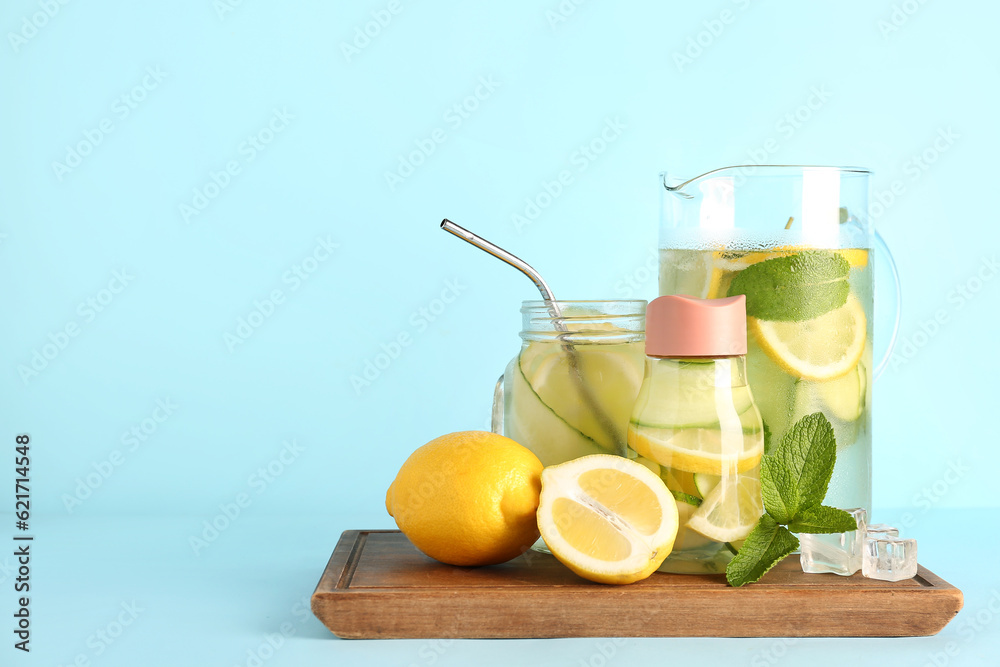 Fototapeta premium Refreshing detox water with lemon, cucumber, and mint in pitcher, bottle, and jar on wooden board