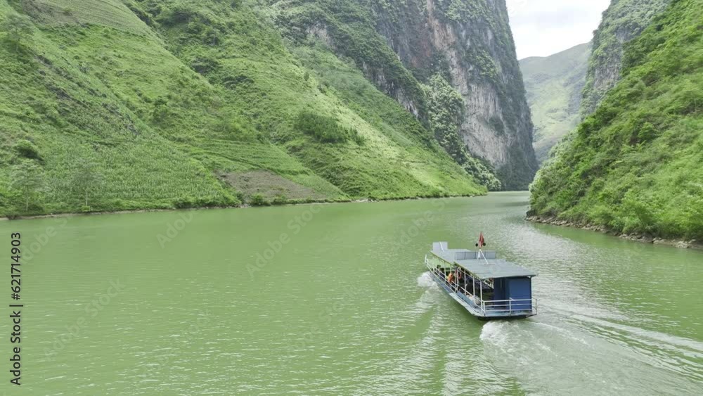Aerial video of river boat tour for tourists on the Nho Quế River in Northern Vietnam with towering cliffs