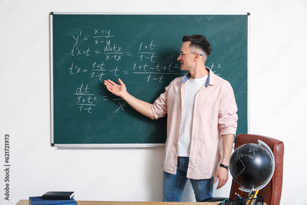 Male Math teacher near chalkboard in classroom Male Math teacher near chalkboard in classroom