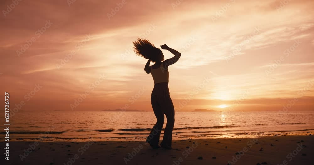 Rear view of young woman winner at sunset, jumping on the beach on sea background, raising her hands in the air, happy and love on life, youth and happiness. Win and success concept