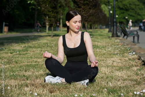 Young woman in black sportswear exercising outdoors. Fitness and healthy lifestyle concept. The white girl does sports in the park. © romeof