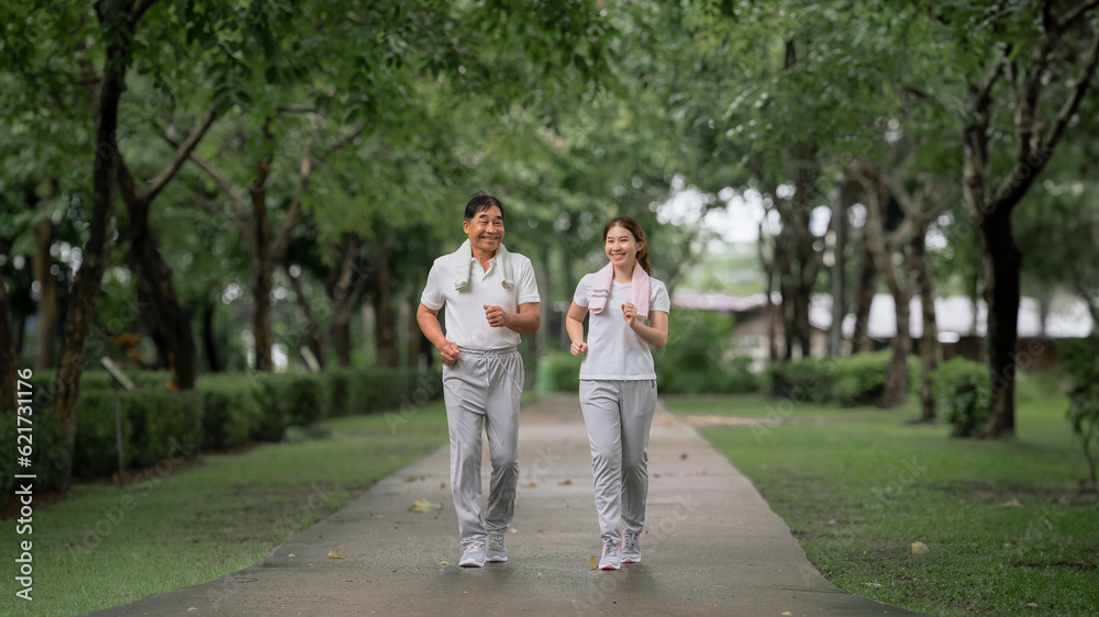 Young beautiful asian woman jogging with her father in park happily, with a smile. Asian woman jogging with her father for health care, park exercise, health care. concept health care life insurance. Young beautiful asian woman jogging with her father in park happily, with a smile. Asian woman jogging with her father for health care, park exercise, health care. concept health care life insurance.