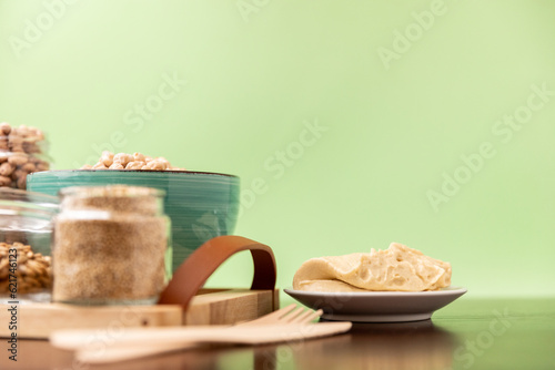 Classic hummus on a small plate on wooden table. Green Background.
