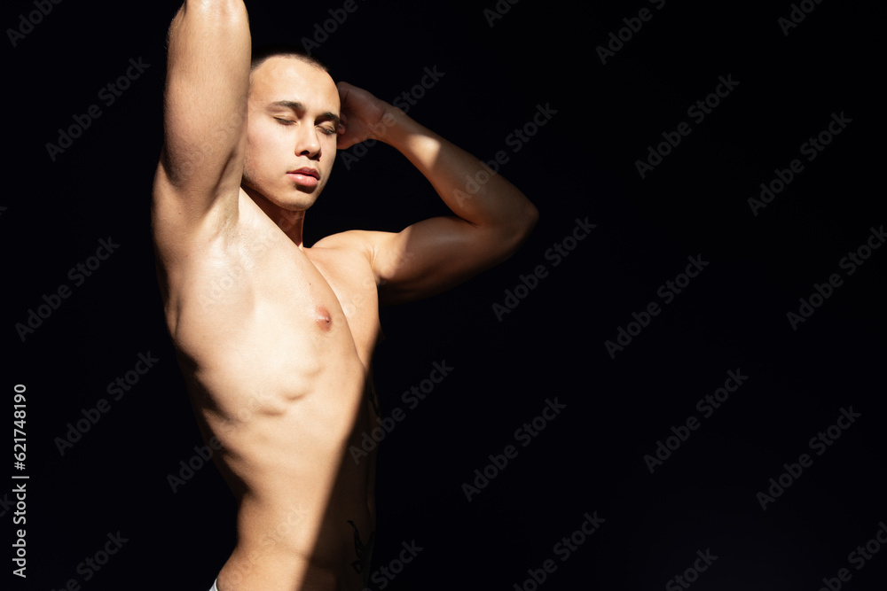 A young attractive guy with a handsome body posing under the sun in the studio. A young attractive guy with a handsome body posing under the sun in the studio.