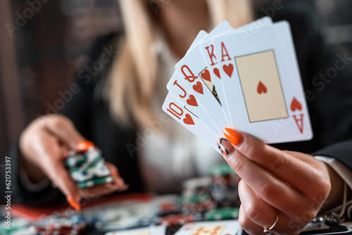 Pretty caucasian woman who plays poker with card and chips in a night casino