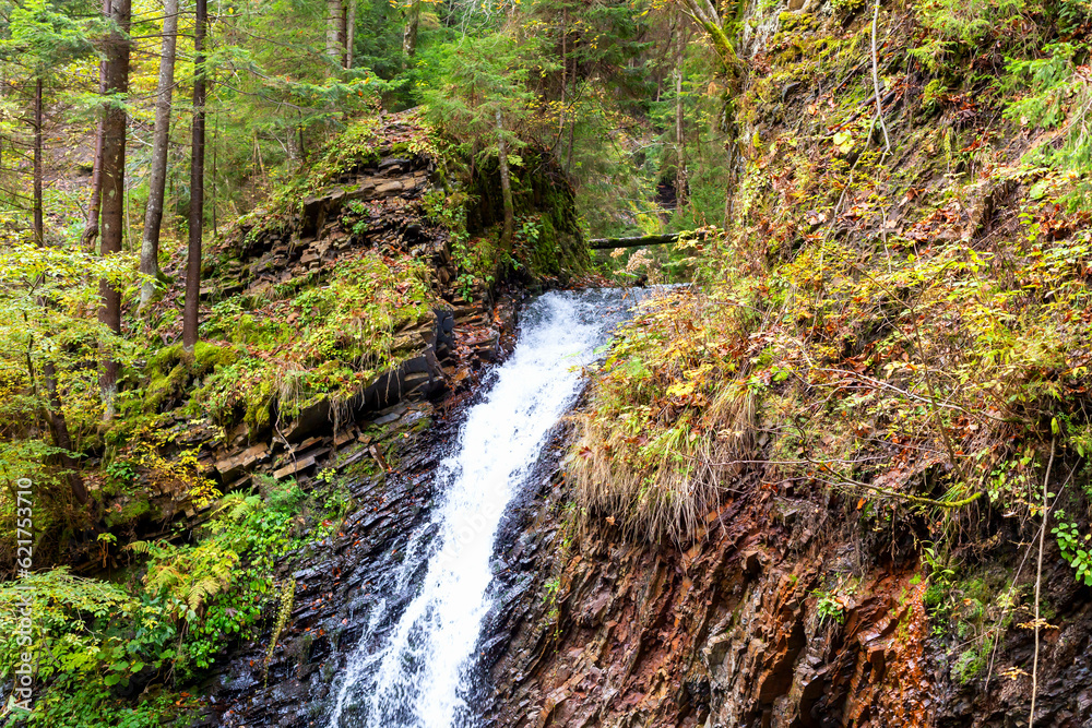 Waterfall in mountains among stones in a beautiful autumn forest. Wildlife. Environmental protection. Selective focus, defocus. Vertically Waterfall in mountains among stones in a beautiful autumn forest. Wildlife. Environmental protection. Selective focus, defocus. Vertically
