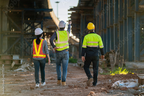Slika na platnu A Professional team of engineers, architects walking, inspecting and working on a highway construction site with a laptop at a road construction site