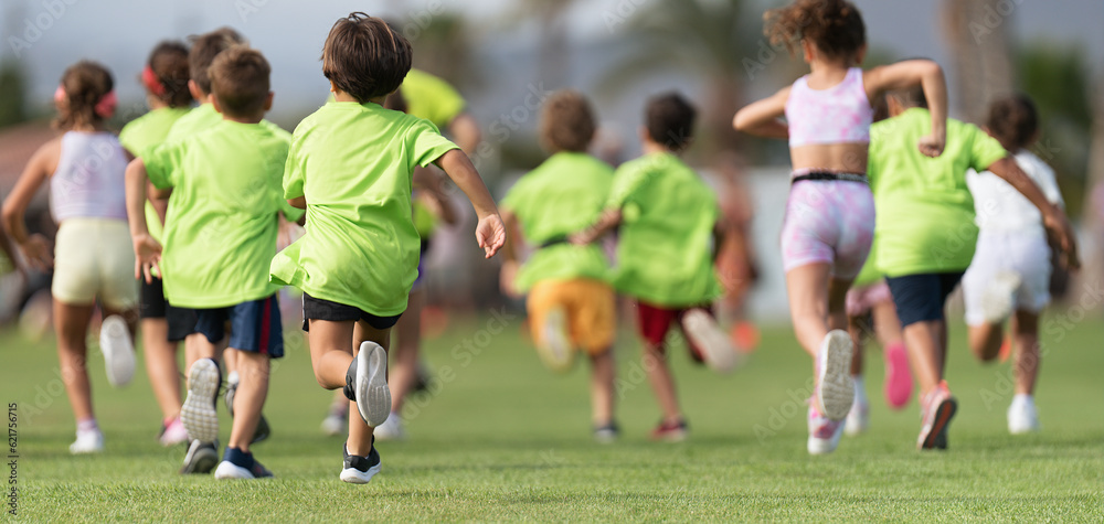 Obraz premium Running children, young athletes run in a kids run race, running on grass detail on legs, running in the light of morning