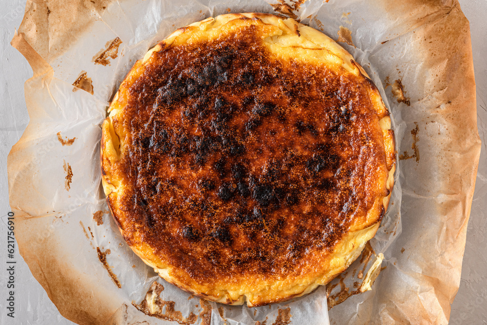 Fototapeta premium Whole basque burnt cheesecake San Sebastian in baking dish on concrete table. top view. Spanish food