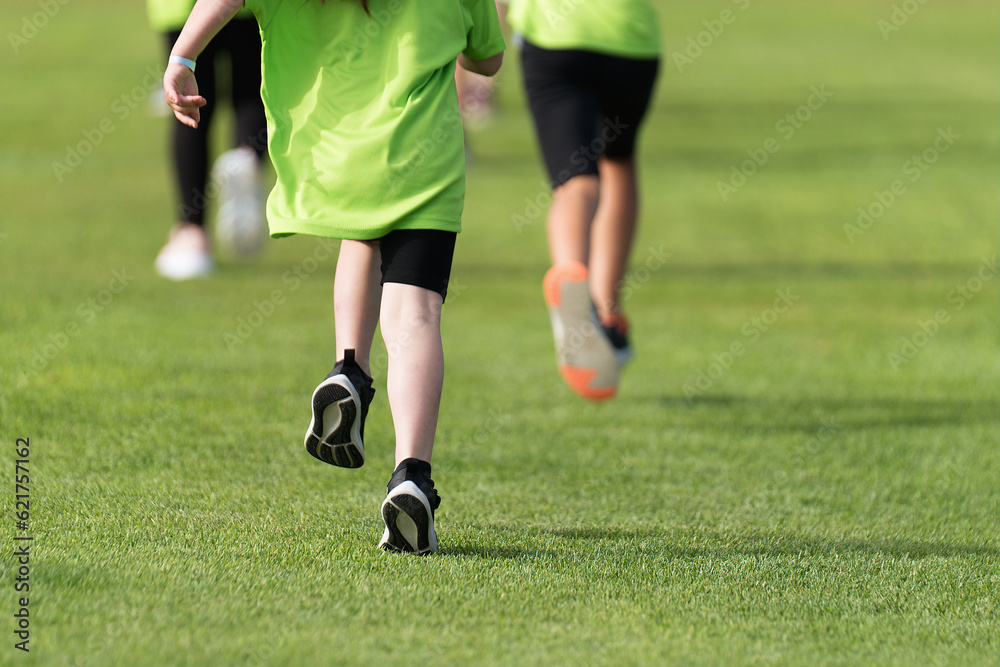 Running children, young athletes run in a kids run race, running on grass detail on legs, running in the light of morning Running children, young athletes run in a kids run race, running on grass detail on legs, running in the light of morning