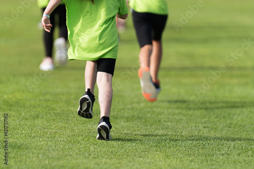 Running children, young athletes run in a kids run race, running on grass detail on legs, running in the light of morning