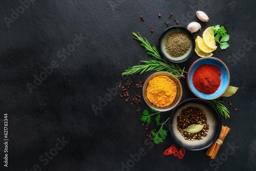 Food cooking ingredients background with various spices in bowls on dark stone table top view