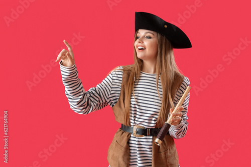 Beautiful female pirate with spyglass pointing at something on red background