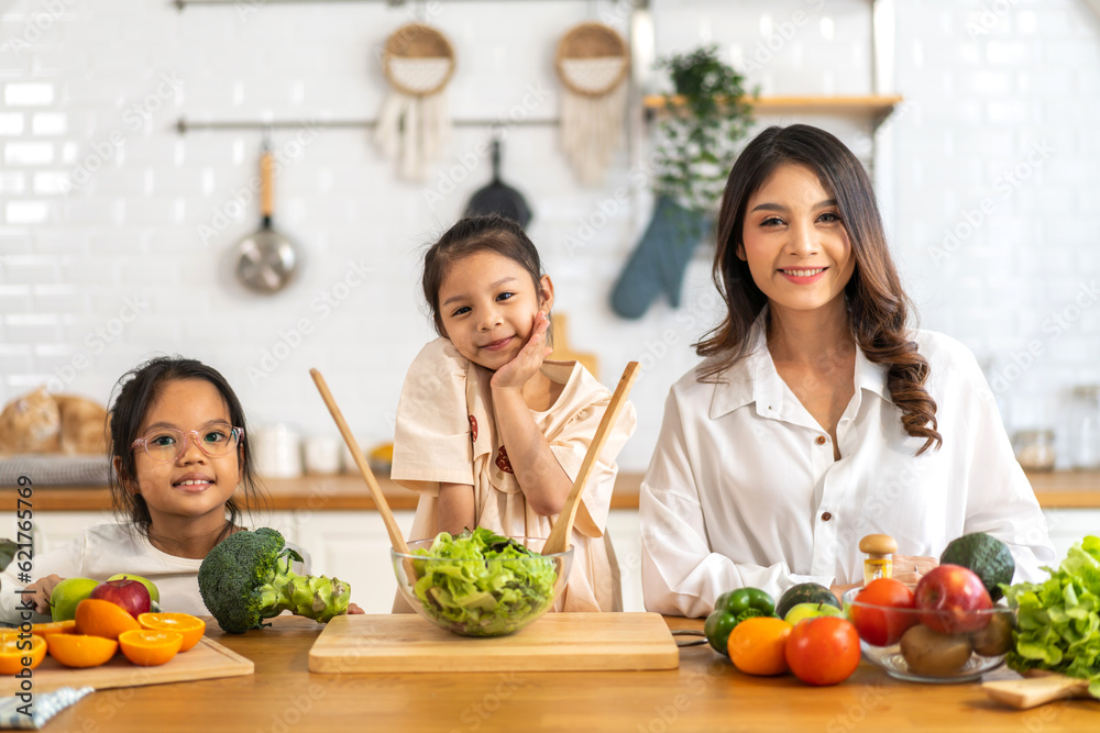 Portrait of enjoy happy love asian family father and mother with little asian girl daughter child having fun help cooking food healthy eat together with fresh vegetable salad ingredient in kitchen