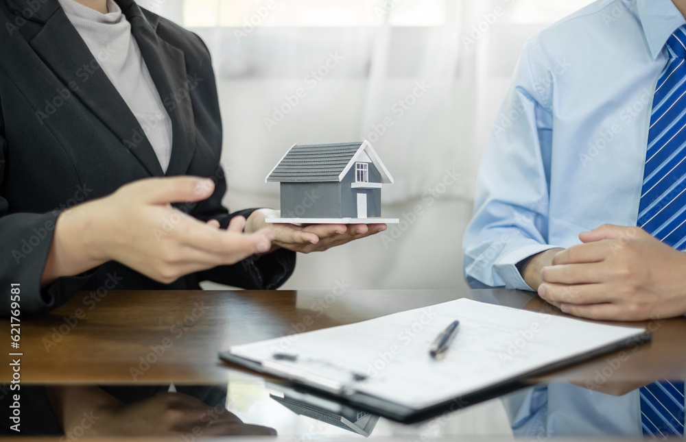A real estate agent with House model is talking to clients about buying home insurance. Home insurance concept A real estate agent with House model is talking to clients about buying home insurance. Home insurance concept
