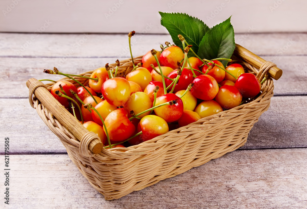 Yellow fresh cherry with leaves in a basket against a gray wooden background. Delicious cherry Yellow fresh cherry with leaves in a basket against a gray wooden background. Delicious cherry