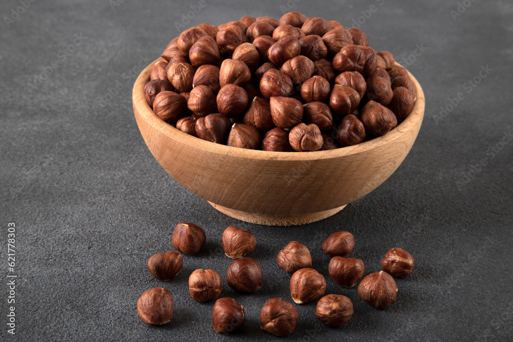 View of a bowl full of hazelnuts on a black background
