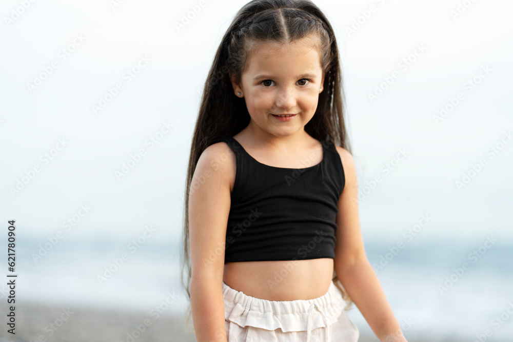 Cute smiling little girl posing on the beach, looking at camera Cute smiling little girl posing on the beach, looking at camera