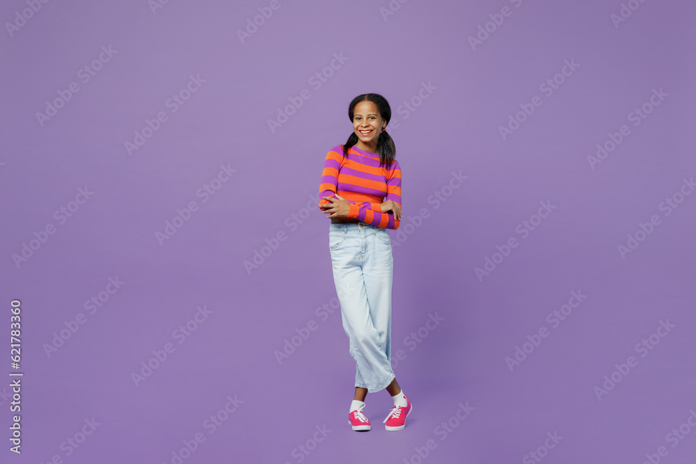 Full body smiling happy fun little kid teen girl 15-16 years old wear striped orange sweatshirt hold hands crossed folded look camera isolated on plain purple background. Childhood lifestyle concept. Full body smiling happy fun little kid teen girl 15-16 years old wear striped orange sweatshirt hold hands crossed folded look camera isolated on plain purple background. Childhood lifestyle concept.