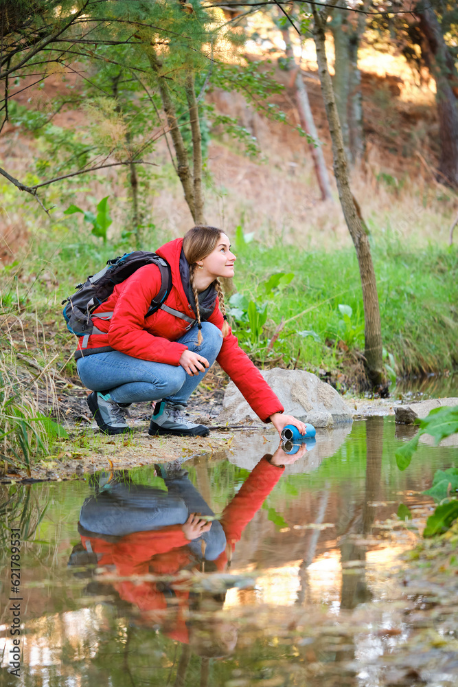 Young female hiker filling water bottle of raw water in a river. Young female hiker filling water bottle of raw water in a river.