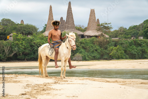 Marapu Sumba Tribe gracefully rides a horse along the shoreline photo