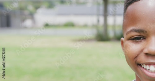 Video half face portrait of smiling african american schoolboy in playing field, with copy space photo