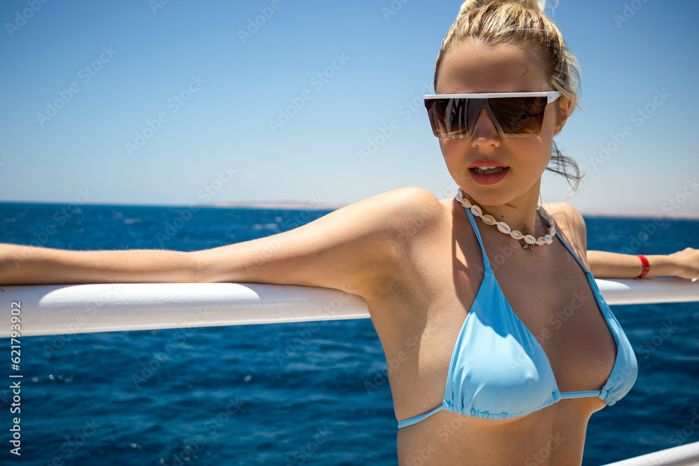 A beautiful girl leaned her arms wide open on the railing of the yacht