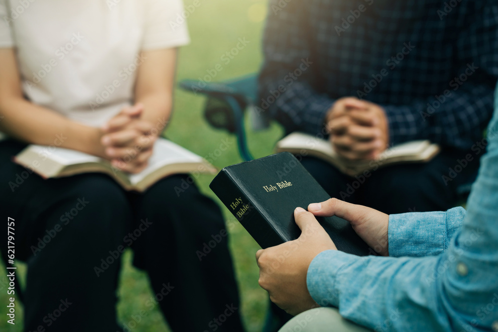 Christian Bible Study Concepts. Christian friend groups read and study the bible together in the park. sharing the gospel with a friend and holding each other's hand praying together. praying to God