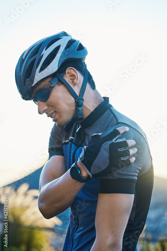 Man, cycling and injury with muscle pain in shoulder, arm or stress with helmet for safety, fitness or exercise. Cyclist, emergency and medical problem in countryside for workout, race or performance