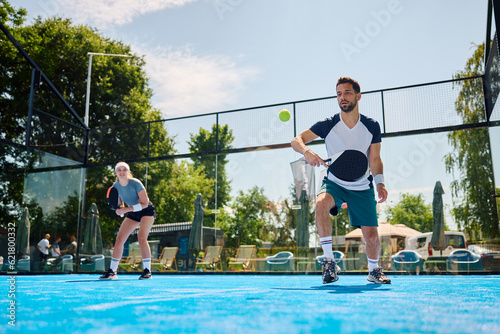 Male athlete plays mixed doubles on paddle tennis court. photo