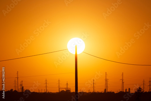 electrical pole against sun at sunset photo