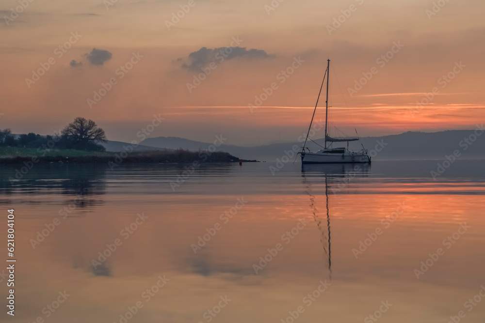 boats reflections and sky in still water at sunset