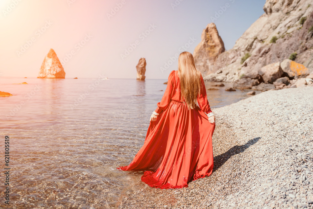 Woman travel sea. Happy tourist in red dress enjoy taking picture outdoors for memories. Woman traveler posing on the rock at sea bay surrounded by volcanic mountains, sharing travel adventure journey Woman travel sea. Happy tourist in red dress enjoy taking picture outdoors for memories. Woman traveler posing on the rock at sea bay surrounded by volcanic mountains, sharing travel adventure journey