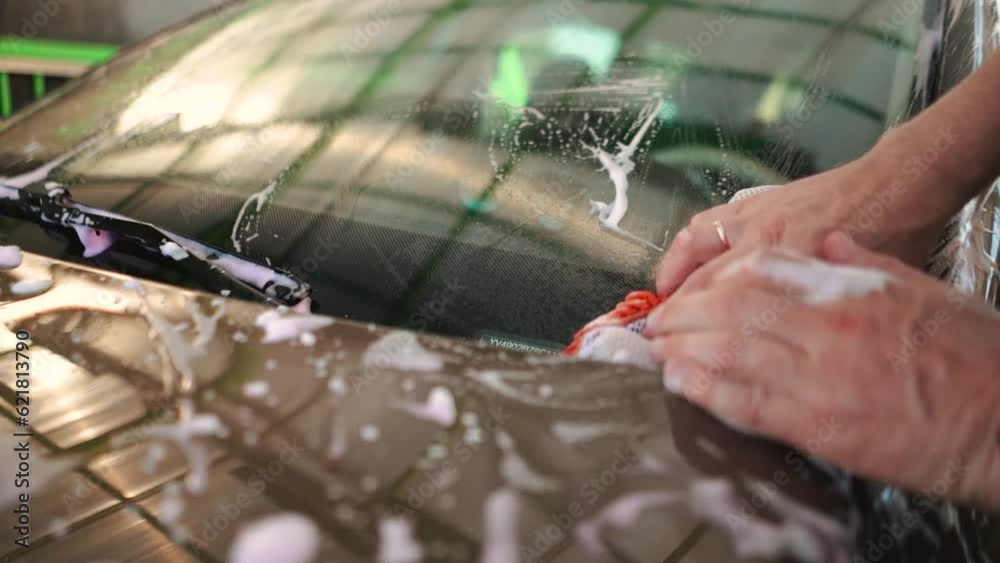 Male driver washing his windshield with nano foam with wipers while
