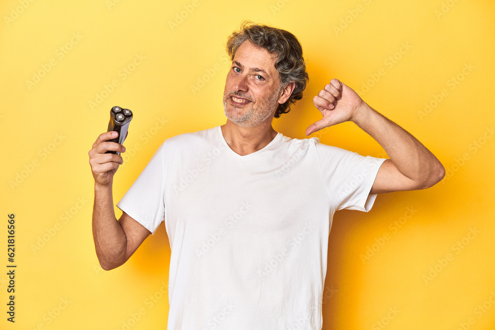 Man holding a razor, yellow studio background feels proud and self confident, example to follow. Man holding a razor, yellow studio background feels proud and self confident, example to follow.