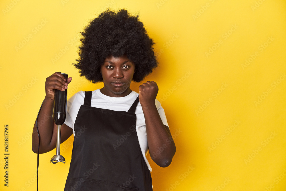 Home-baking woman with mixer, ready to create showing fist to camera, aggressive facial expression. Home-baking woman with mixer, ready to create showing fist to camera, aggressive facial expression.