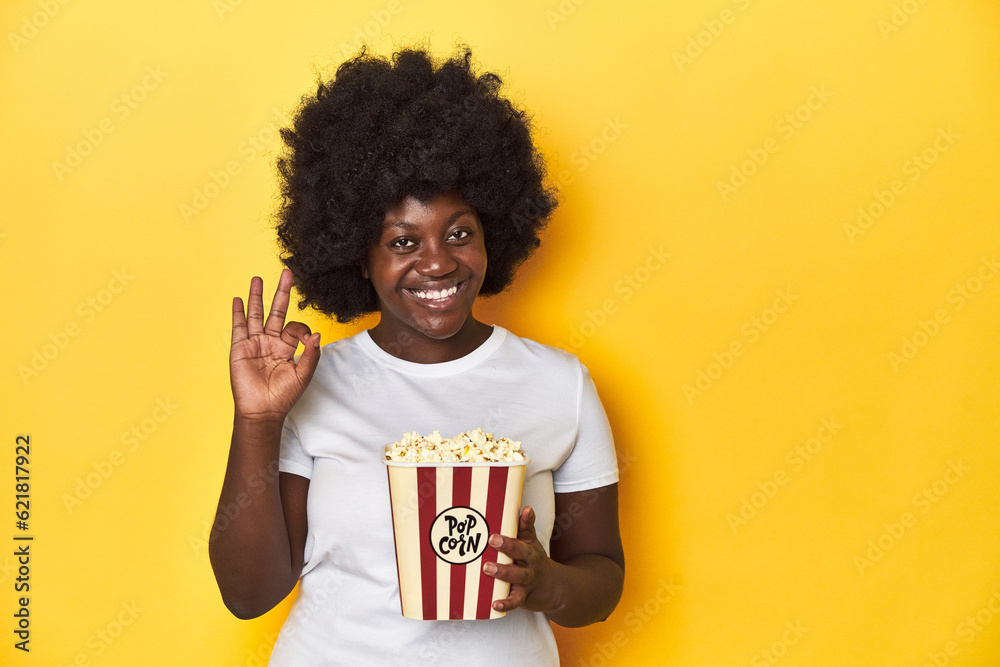 Movie night concept with woman holding popcorn cheerful and confident showing ok gesture. Movie night concept with woman holding popcorn cheerful and confident showing ok gesture.