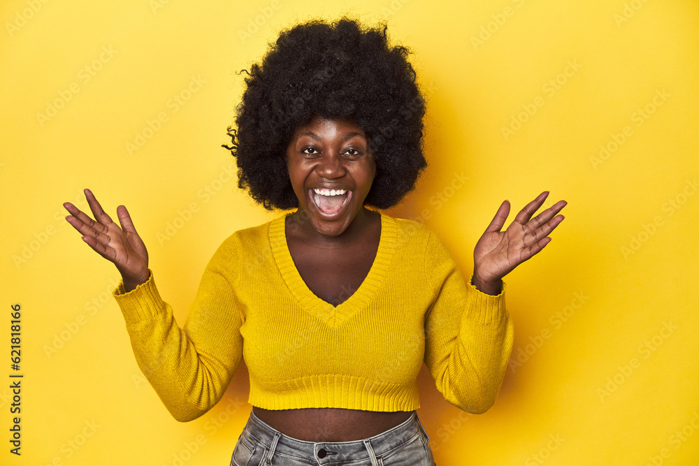 African-American woman with afro, studio yellow background celebrating a victory or success, he is surprised and shocked. African-American woman with afro, studio yellow background celebrating a victory or success, he is surprised and shocked.
