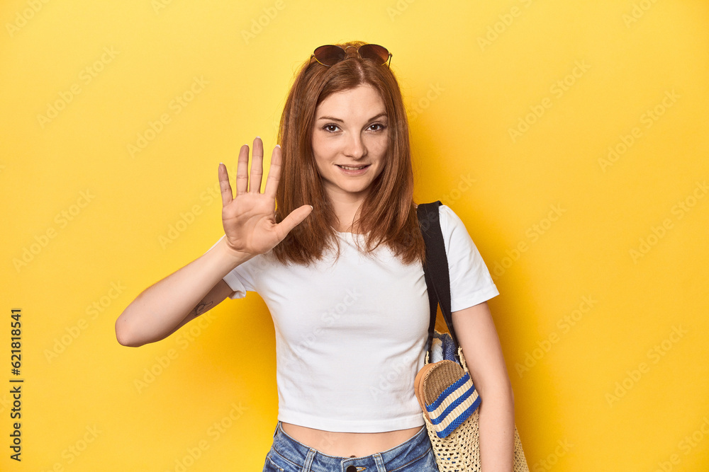 Summer concept redhead with beach bag in studio smiling cheerful showing number five with fingers. Summer concept redhead with beach bag in studio smiling cheerful showing number five with fingers.
