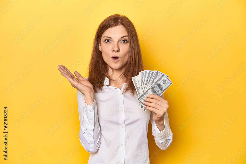 Redhead with dollar bills, cash in hand surprised and shocked. Redhead with dollar bills, cash in hand surprised and shocked.